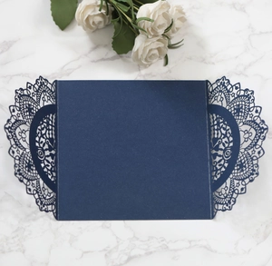 Detailed laser-cut dark blue floral wedding invitation cover on white marble