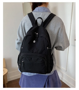 Detailansicht eines schwarzen Nylon-Rucksacks mit mehreren Reißverschlussfächern am Modell