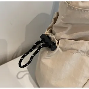 Dettaglio della chiusura con coulisse regolabile e fermacorda su borsa tote in nylon beige
