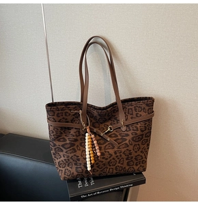 Close-up of leopard print suede tote bag with leather handles and colorful bead charm