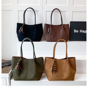 Detail view of four suede tote bags with wooden beaded tassels in various autumn colors
