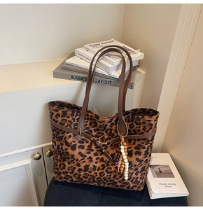 Detail of leopard print suede tote bag with brown straps and colorful beaded pendants