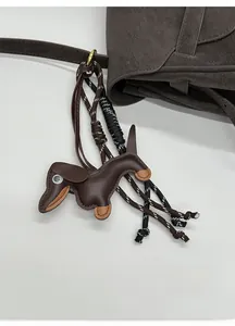 Close-up of a brown dachshund leather bag charm with detailed stitching and woven lanyard