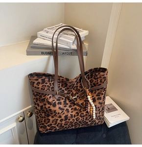 Detail of leopard print suede tote bag with brown leather handles and beaded tassel charm