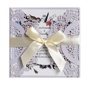 Detail of laser-cut lavender wedding invitation with beige silk ribbon and floral insert