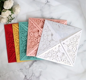 Detailed laser-cut floral patterns on colorful folded wedding invitation cards