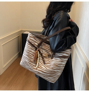 Detail of zebra pattern suede tote bag with ethnic beaded tassel and leather straps