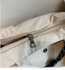 Dettaglio della cerniera in metallo e della fodera interna della borsa tote beige
