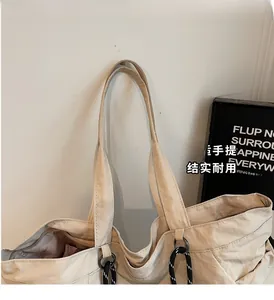 Dettaglio della borsa tote in tela beige con anello di metallo e corda a righe laterale