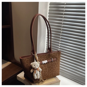 Detail of leopard print tote bag with metal hardware and plush bear charm
