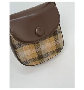 Detailed view of the vintage brown leather and plaid fabric patchwork saddle bag