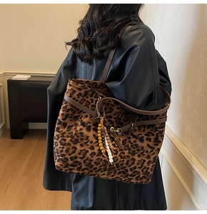Close-up of leopard print suede tote bag with brown leather straps and colorful bead charm