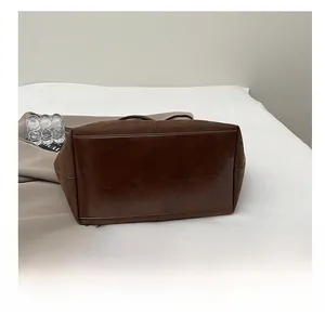 Bottom detail showing durable leather stitching and brown suede of a large tote bag