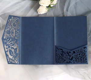 Macro shot of navy blue laser-cut wedding invitation featuring intricate floral patterns