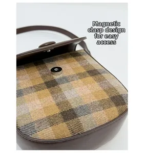 Detail of the magnetic buckle closure on a vintage plaid wool saddle shoulder bag