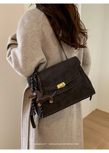 Detail of retro suede shoulder bag featuring gold square lock and dachshund charm