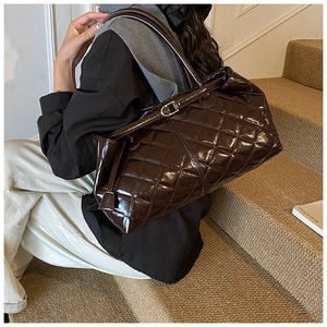 Gros plan sur le sac cabas matelassé en cuir verni marron avec boucles dorées