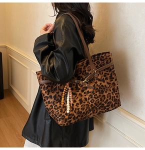 Close-up of leopard print tote bag with brown leather straps and colorful beaded tassel
