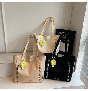 Three canvas tote bags with LifeLife text and yellow flower charms in neutral colors