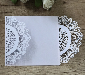 Macro detail of laser-cut white wedding invitation pocket with intricate floral pattern