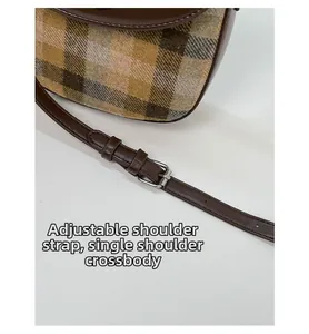 Detail of adjustable strap on brown leather and camel plaid saddle bag for shoulder or crossbody wear