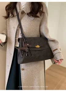 Close-up of retro dark brown crossbody bag with gold twist lock and dachshund charm