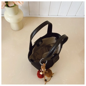 Dettaglio dell'interno della borsa a secchiello nera con chiusura magnetica e charm boho