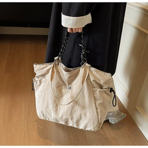 Dettaglio di una grande borsa tote in nylon beige con tasche laterali a coulisse e manici