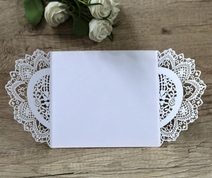 Detail of laser-cut lace pattern on white pearlescent paper wedding invitation card