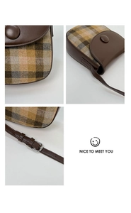Detail of retro saddle bag showing plaid tweed fabric and brown leather flap with buckle