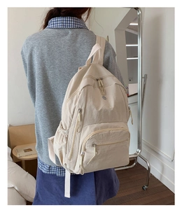 Detailansicht der Rückseite eines beigen Nylon-Rucksacks mit verstellbaren Schultergurten