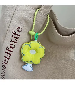 Close-up of yellow flower fabric charm with blue stitching on a canvas tote bag strap