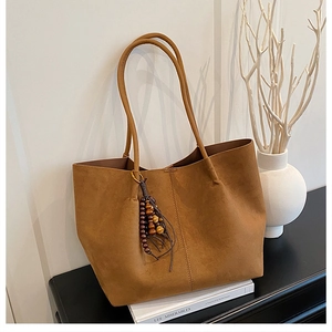 Brown suede tote bag with leather tassel and wood beads shown in lifestyle setting