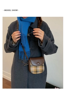 Detail view of a vintage plaid saddle bag with brown leather strap on a grey coat