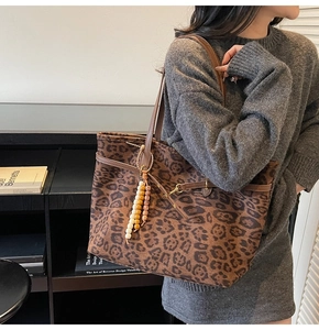 Detail of leopard print tote bag with brown leather straps and bohemian beaded charm
