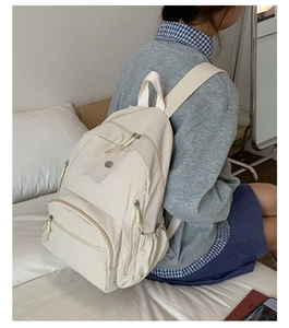 Detailansicht des cremeweißen Nylon-Rucksacks mit Kordelzugtaschen an einem Modell