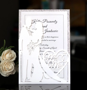 Detail of laser-cut wedding invitation featuring Mr & Mrs heart silhouette and silver glitter
