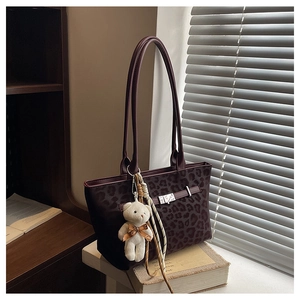Detail of leopard print tote bag with metal buckle and plush bear charm by the window