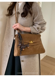 Close-up of retro brown suede tote featuring metal turn-lock and dachshund charm