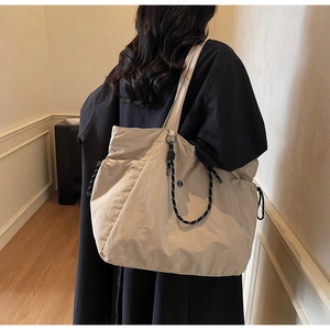 Dettaglio della grande borsa tote beige con coulisse intrecciata bianca e nera di lato