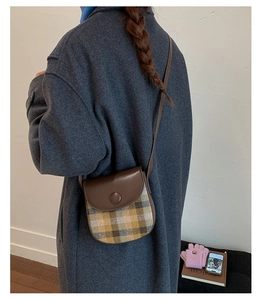 Detail of vintage plaid saddle bag with leather flap and large round buckle closure
