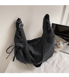 Detail of adjustable black shoulder strap and silver metal buckle on checkered hobo bag