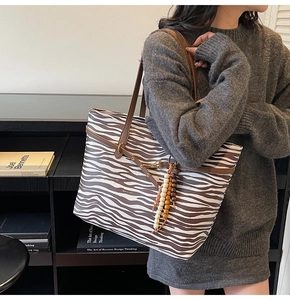 Zebra pattern tote bag with brown leather straps and beaded charm on model