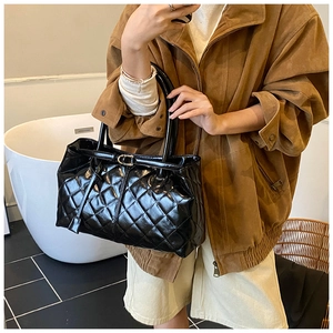 Détail d'un grand sac cabas matelassé noir avec boucle dorée en studio chaleureux