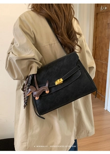 Detail of black retro suede shoulder bag with gold hardware and brown puppy charm