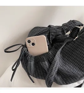 Detail view of the side drawstring pocket on a checkered canvas bag with a mobile phone