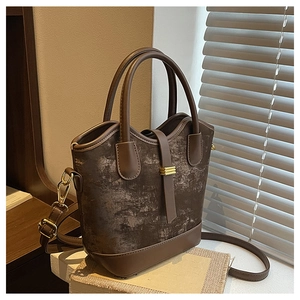 Détails d'un sac seau marron foncé avec fermoir en métal doré et texture en cuir synthétique