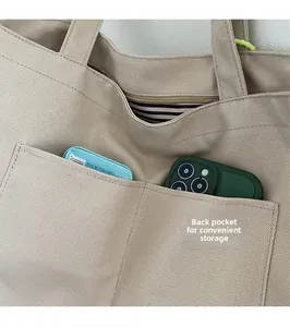 Detail of canvas tote bag featuring back pockets for phone storage and striped lining