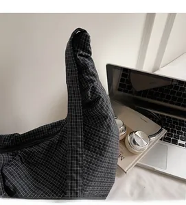 Detail of checkered canvas hobo bag with zipper closure on a desk with laptop