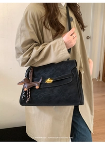Detail of black suede shoulder bag with gold twist lock and cute dog bag charm